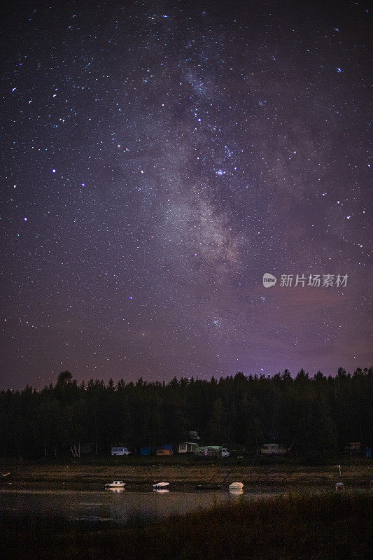 夜晚，在星空和银河下，湖边是房车露营车和房车的露营地