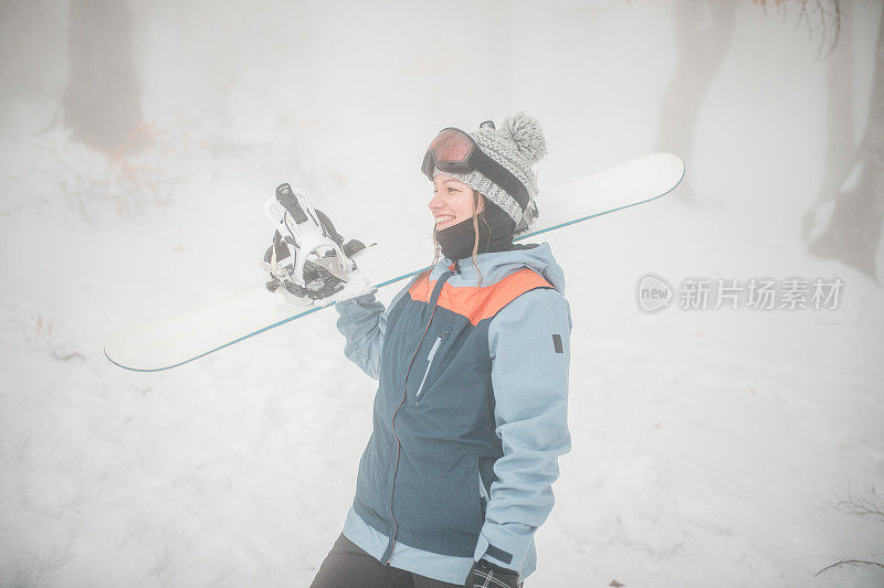 一个微笑的女人正准备在山上滑雪