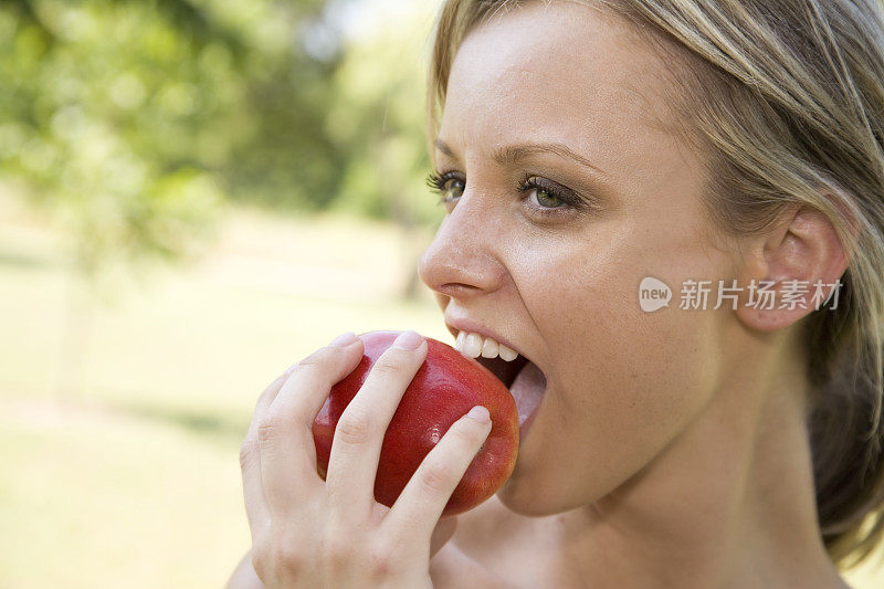 年轻漂亮的女人咬了一大口苹果