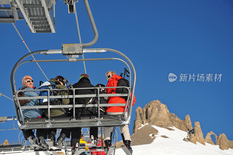 两个老人坐在滑雪椅上向后看。