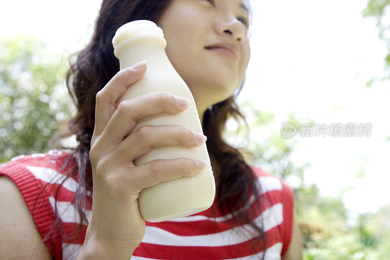 手里拿着一瓶牛奶的年轻女子