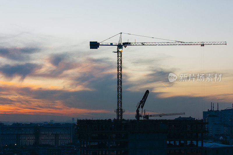 日落时分，起重机在建筑工地工作，建造和搬运