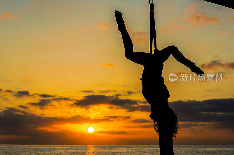 海上日出时空中的女丝绸舞者