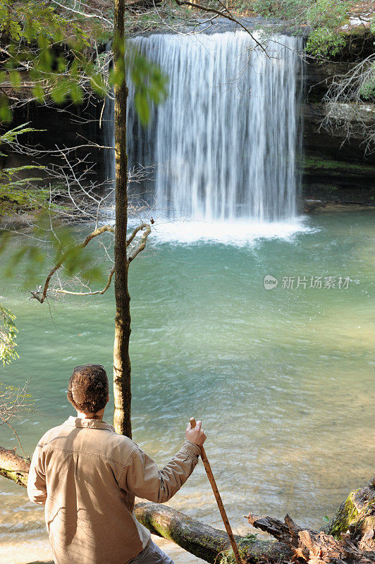 男子与远足手杖欣赏瀑布