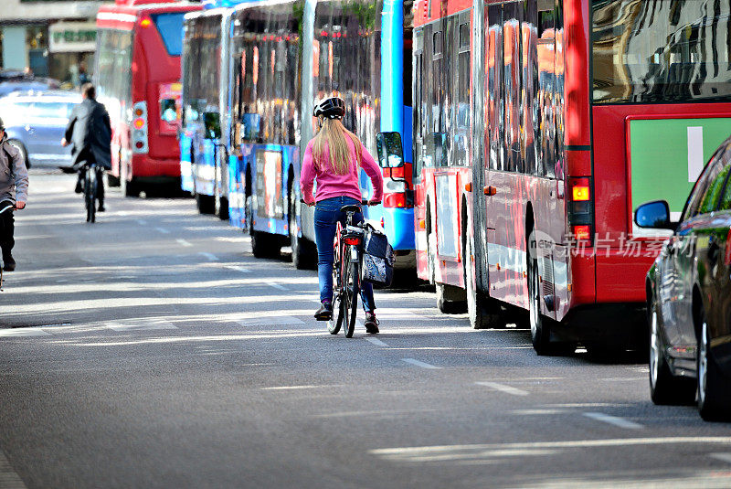 骑自行车的金发女人和一排公共汽车