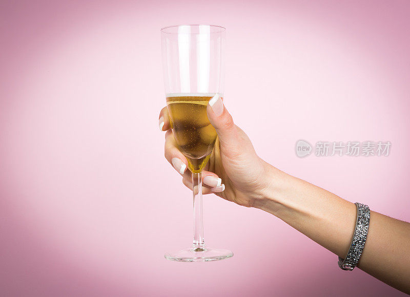 女人手里拿着一杯香槟酒，孤立上一片粉红
