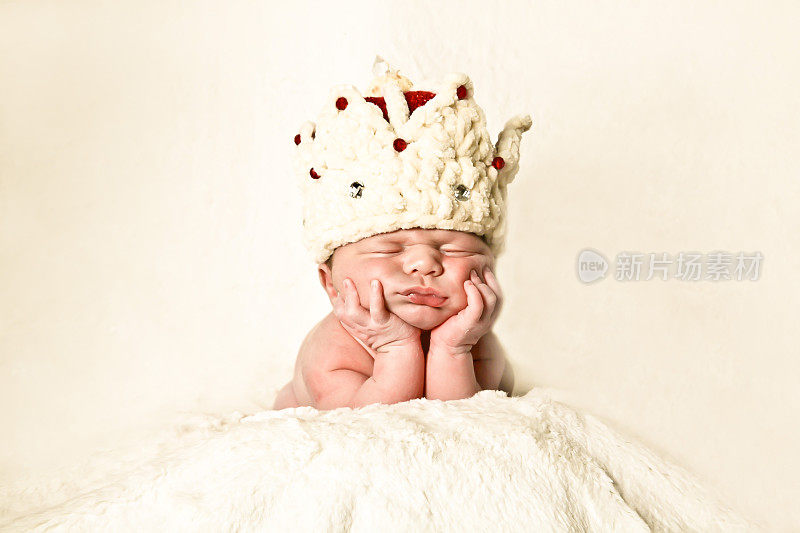 刚出生的婴儿戴着皇冠，趴在手上睡觉