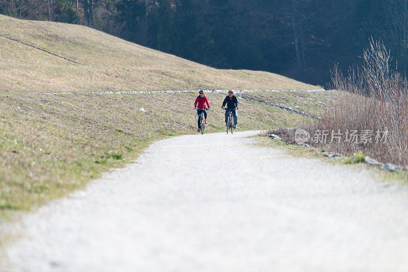 活跃的夫妇在风景优美的道路上骑自行车。