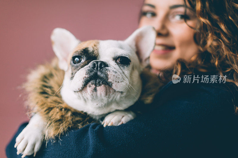 一个自信的女人抱着一只法国斗牛犬