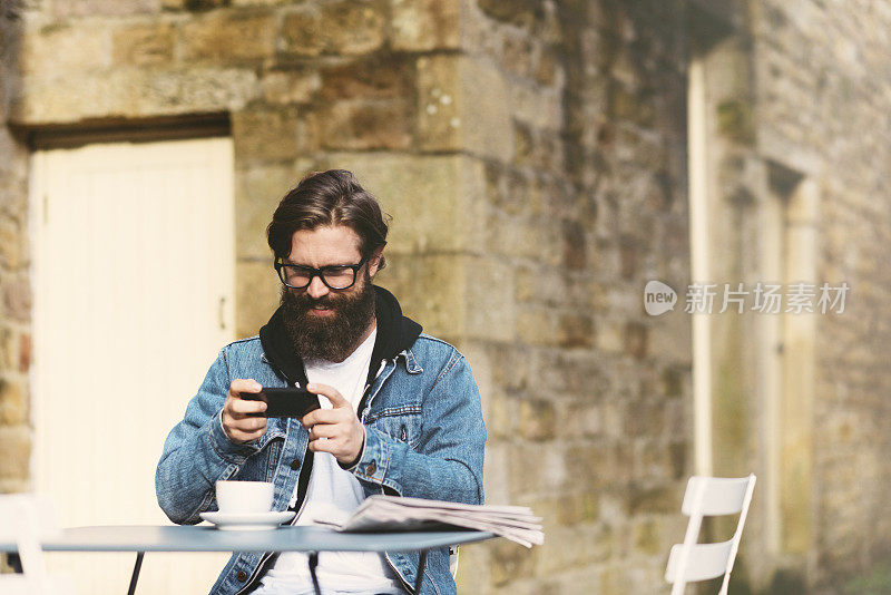 大胡子男子用手机拍咖啡