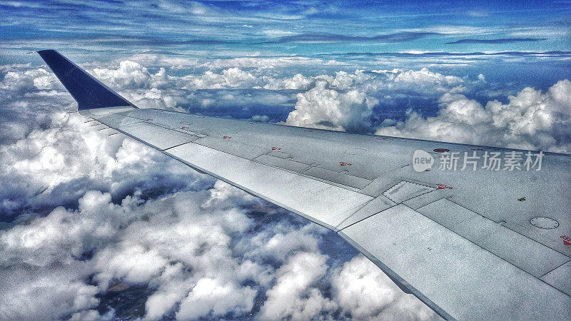 大型飞机机翼在天空中散落的蓬松云上飞行