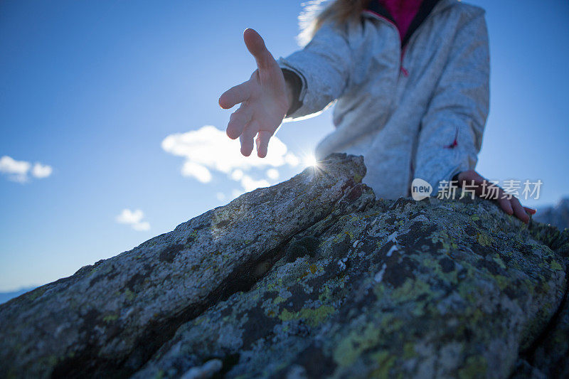 一名年轻女子向山顶伸出手来