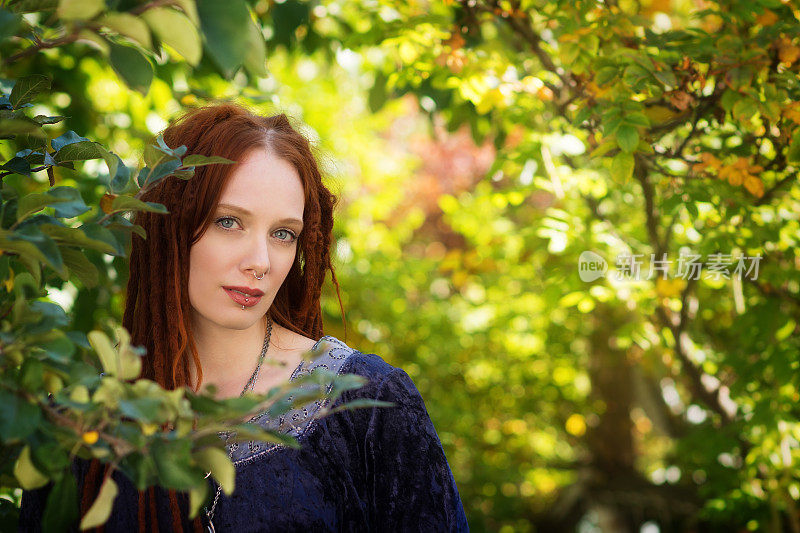 漂亮的红发姑娘从花园里的藤蔓中望出去。