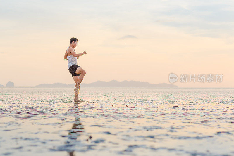 年轻的亚洲男子训练空手道和踢拳击在海滩