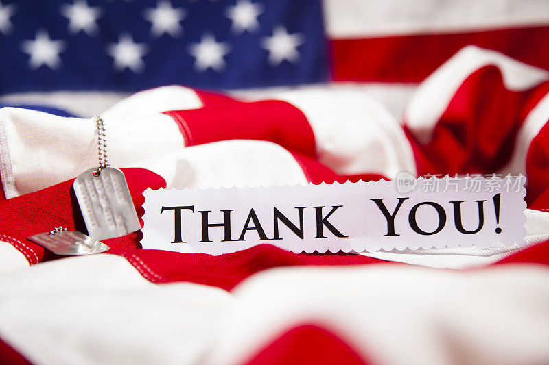 在“谢谢你”的纸条旁边放着美国军方的身份识别牌。美国国旗。