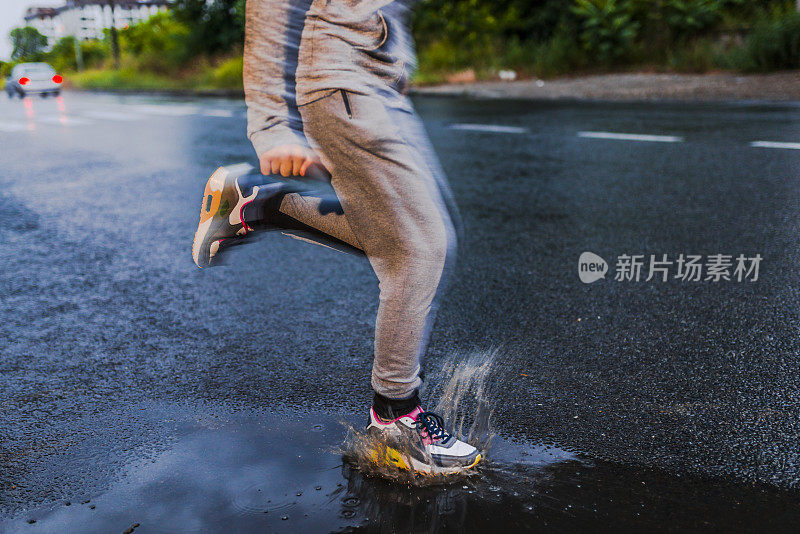 在雨天，年轻女子在沥青操场上跑步