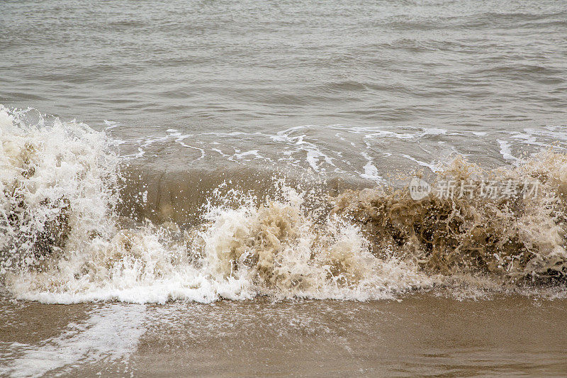 泥泞的海浪在海滩上冲浪