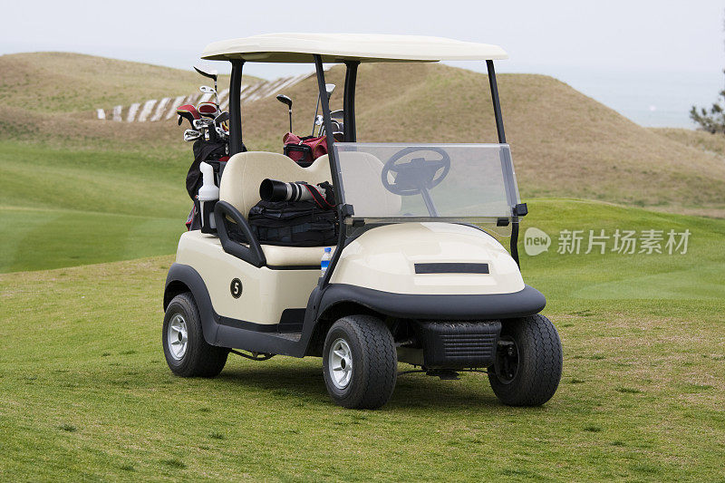 高尔夫球车带着球杆和摄像机在球场上行驶
