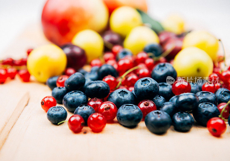 红醋栗和蓝莓与其他水果在木板的背景