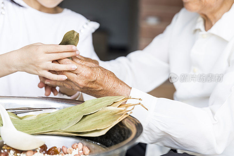 奶奶教孙女包粽子。