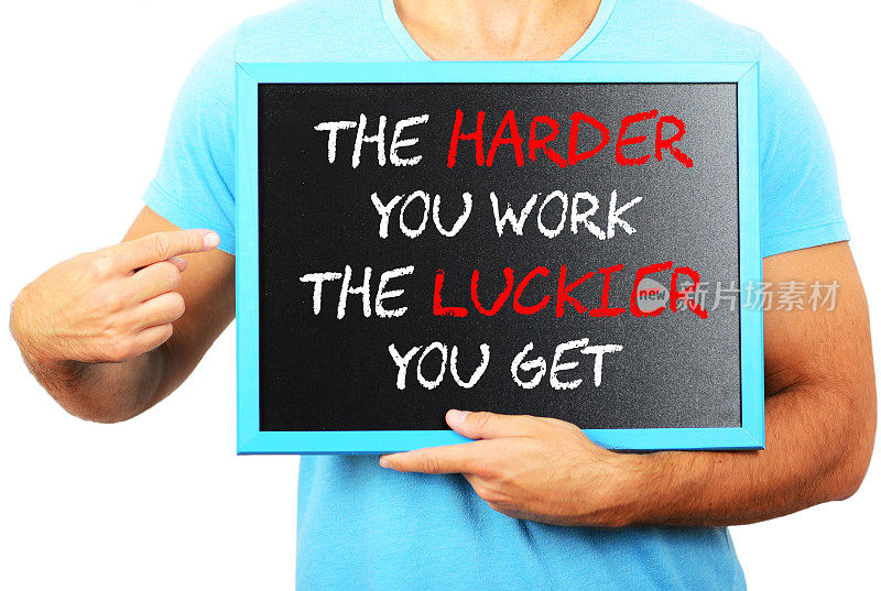 一个人手里拿着黑板，指着“你越努力，你就越幸运”这个字