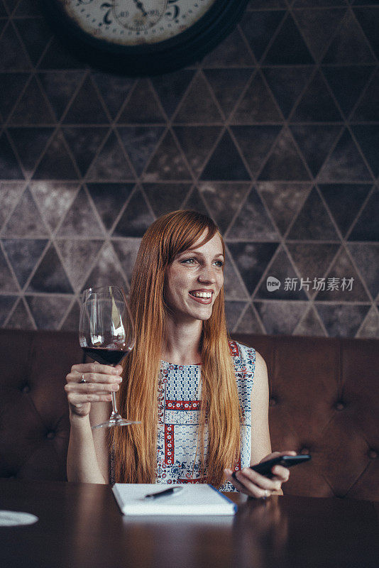 聪明的女人喝着红酒，在社交媒体上分享印象