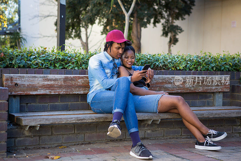 一对黑人夫妇在看他们手机上的照片