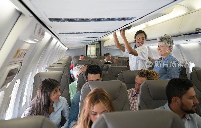 在飞机上帮助一位年长女士搬运行李的空乘人员