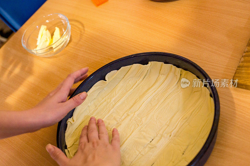 自制糕点的生面团在妇女手中。用手工制作馅饼面团的过程