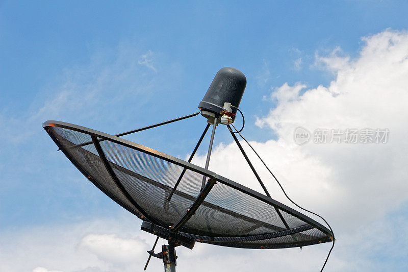 屋顶上的黑色碟形卫星接收器，背景是白云和蓝天，通讯和技术的意义。