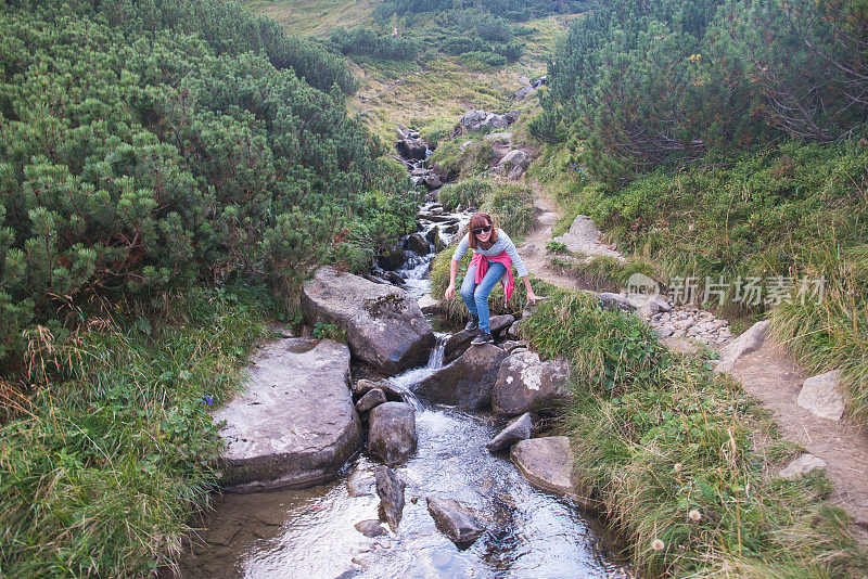的旅程。山上的小溪。女孩拨动手中的水。