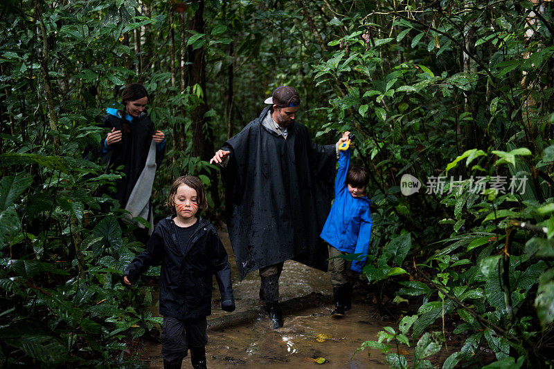 一个家庭带着年幼的孩子在亚马逊丛林的雨和泥中行走。