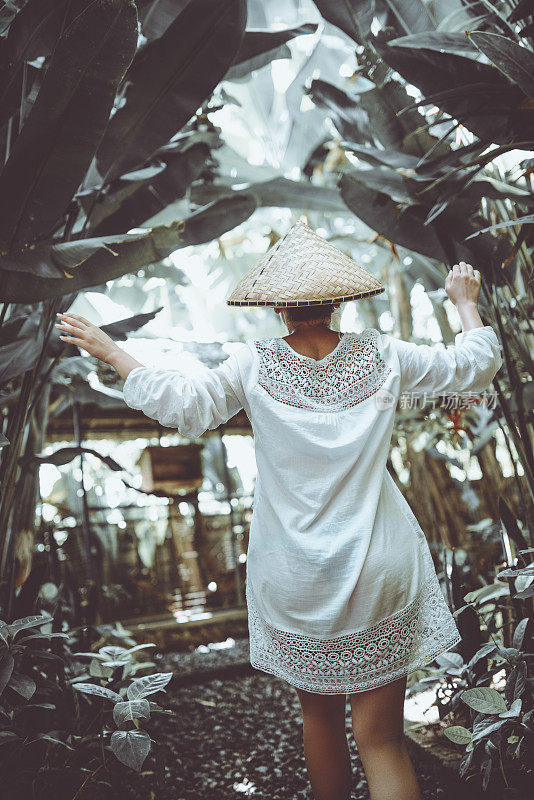 戴着传统草帽的亚洲女性在竹林中行走