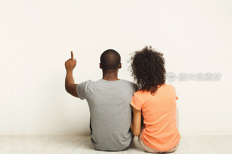 一对黑人夫妇坐在地板上，抬头看