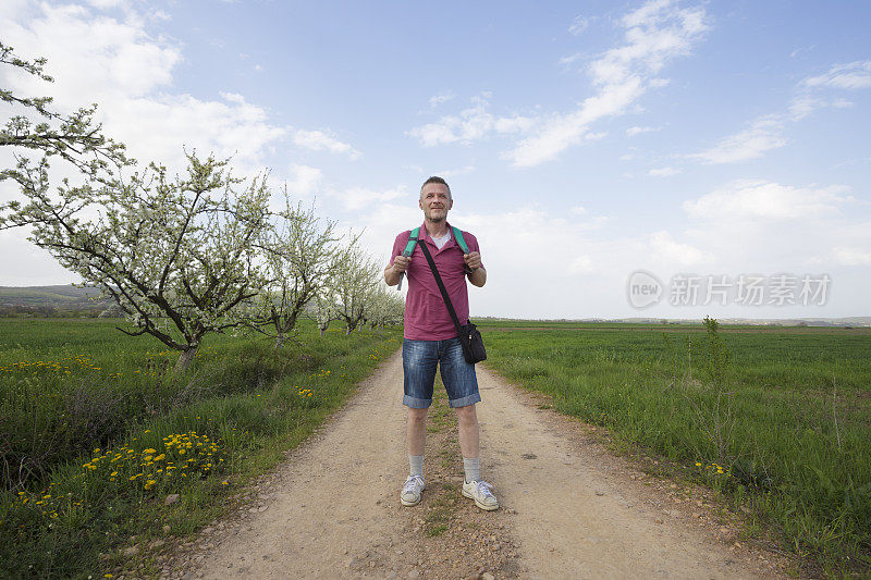 成年男子背着背包在乡村大自然中徒步旅行