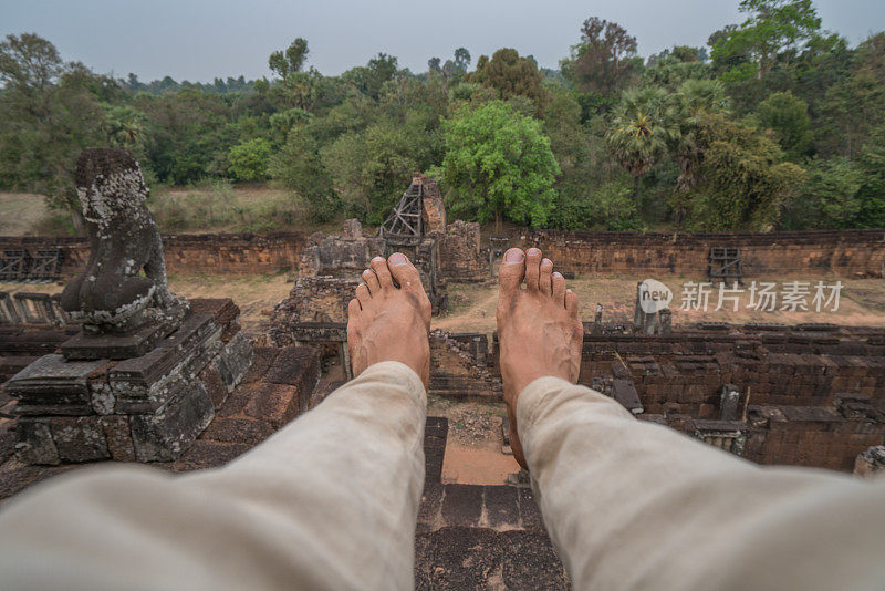 坐在柬埔寨吴哥窟古庙顶上的男人的视角