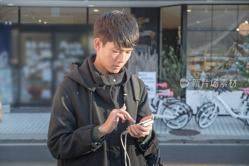 年轻的日本男子用手机与在日本的朋友聊天