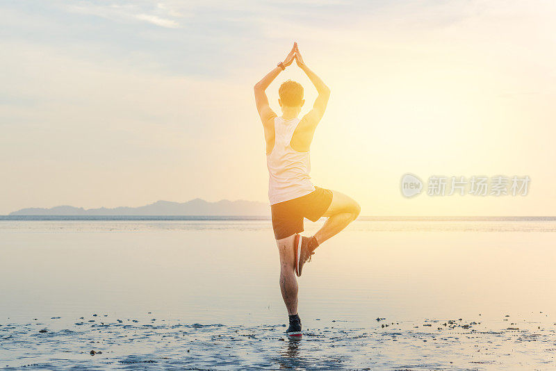 年轻的亚洲男子在日落海滩做瑜伽运动