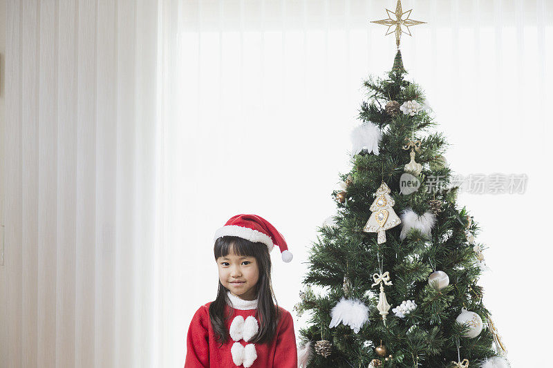 女孩穿着圣诞老人的服装装饰圣诞树