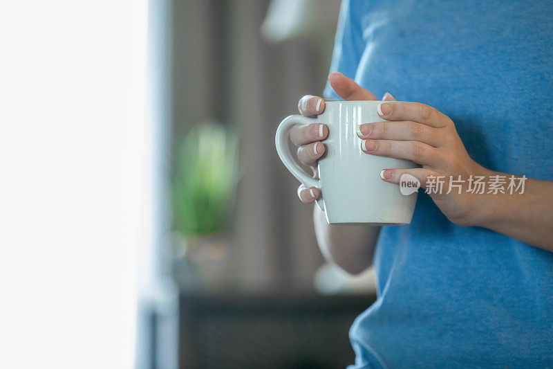 一个修指甲的女人在家里端着一杯咖啡