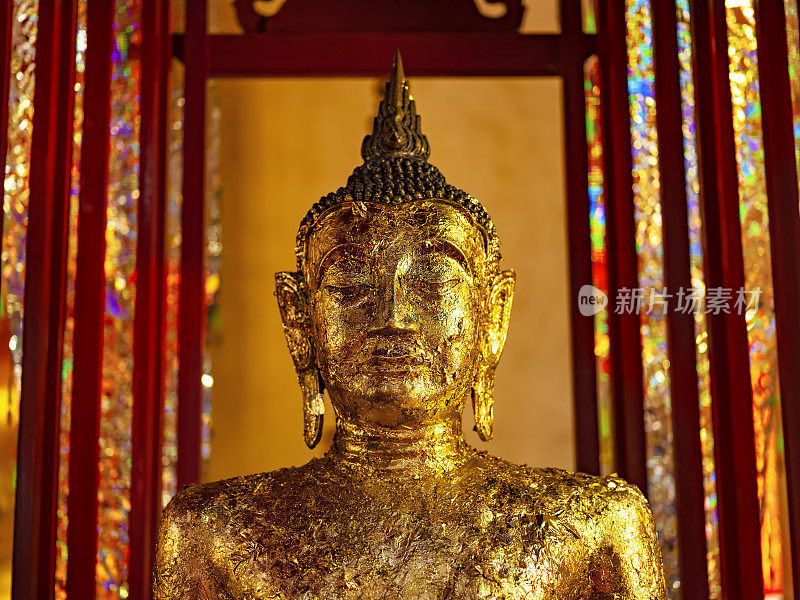 在一个典型的泰国佛教寺庙的地面上，一尊覆盖着金箔的佛像。