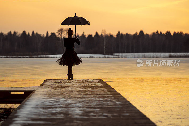 美丽的女人在冰湖边打着伞