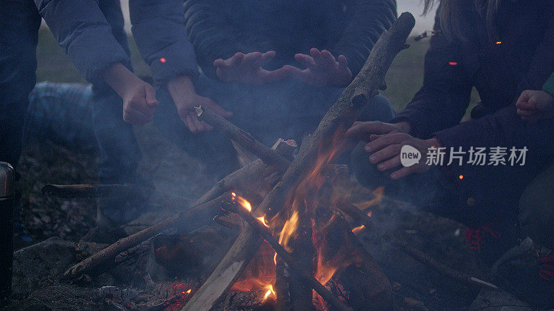 一家人在篝火旁取暖。冬天的乐趣。城市的河滨