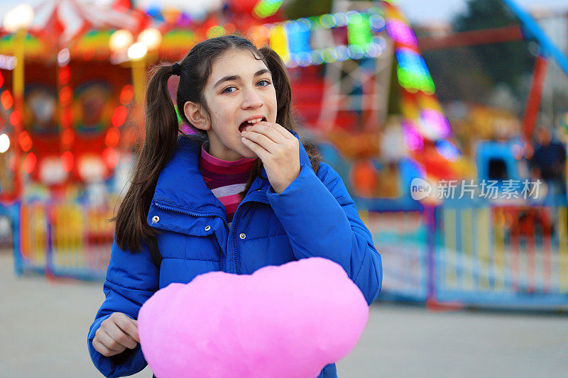 在游乐场吃棉花糖的女孩