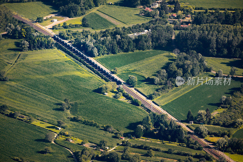 从空中鸟瞰图，货运铁路轨道跨越在斜线的法国乡村在夏天，在充满活力的绿色田野的中部Ain部门，奥弗涅-罗纳-阿尔卑斯地区