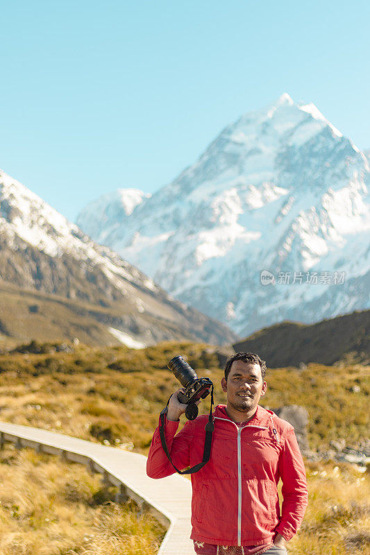 新西兰库克山;一个徒步旅行者在库克山的一条徒步小径上的阳光下拍照。