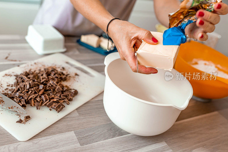 女人的手准备烘焙原料与巧克力片，黄油和面粉库存照片