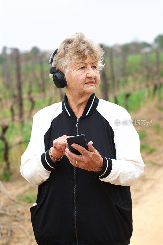 一位老年妇女一边锻炼一边用手机听着耳机里的音乐