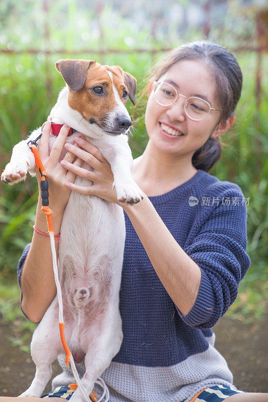 亚洲女孩与他们的宠物狗放松和花时间一起在公园户外