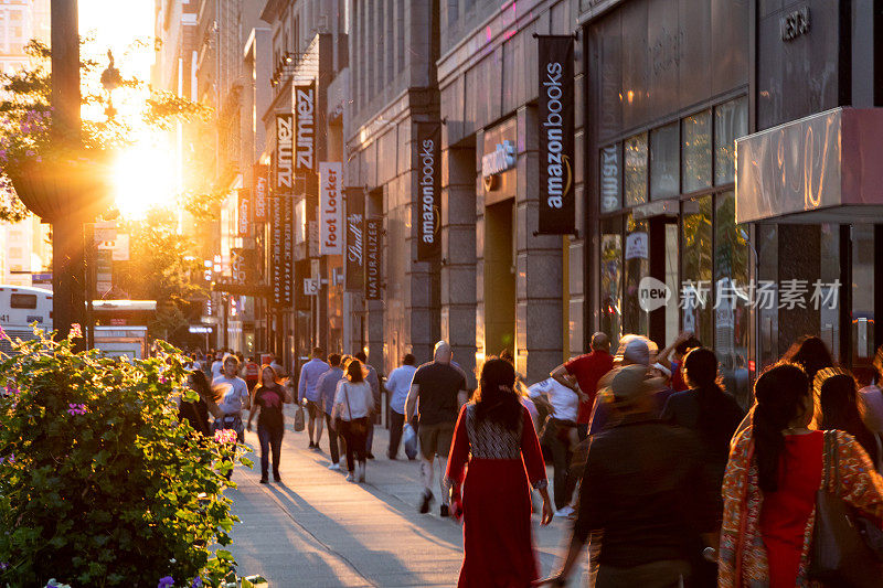 阳光照耀着形形色色的人群，他们走过纽约市34街的人行道上的商店和商店